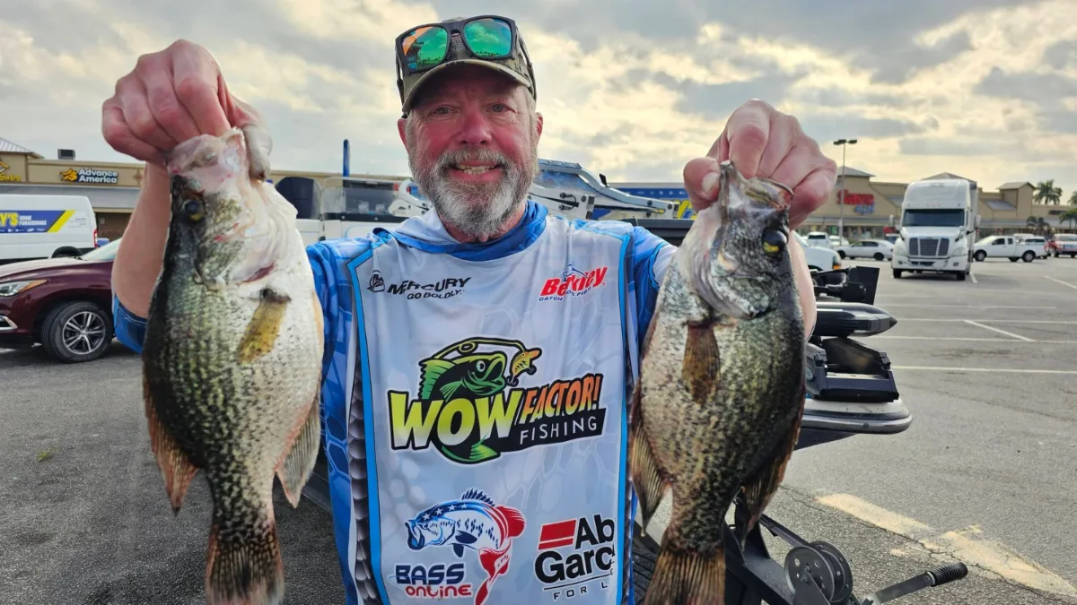 Angler holding two black crappie on a Lake Okeechobee crappie fishing trip