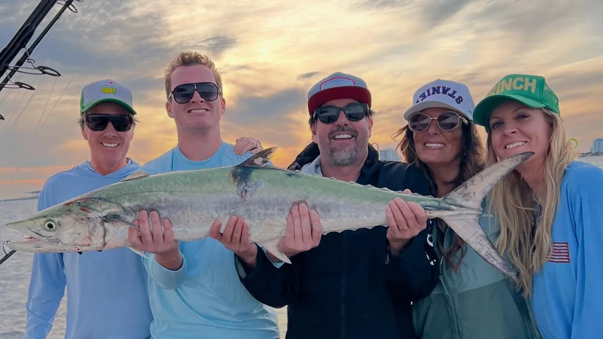 Group holding a large kingfish after an offshore charter